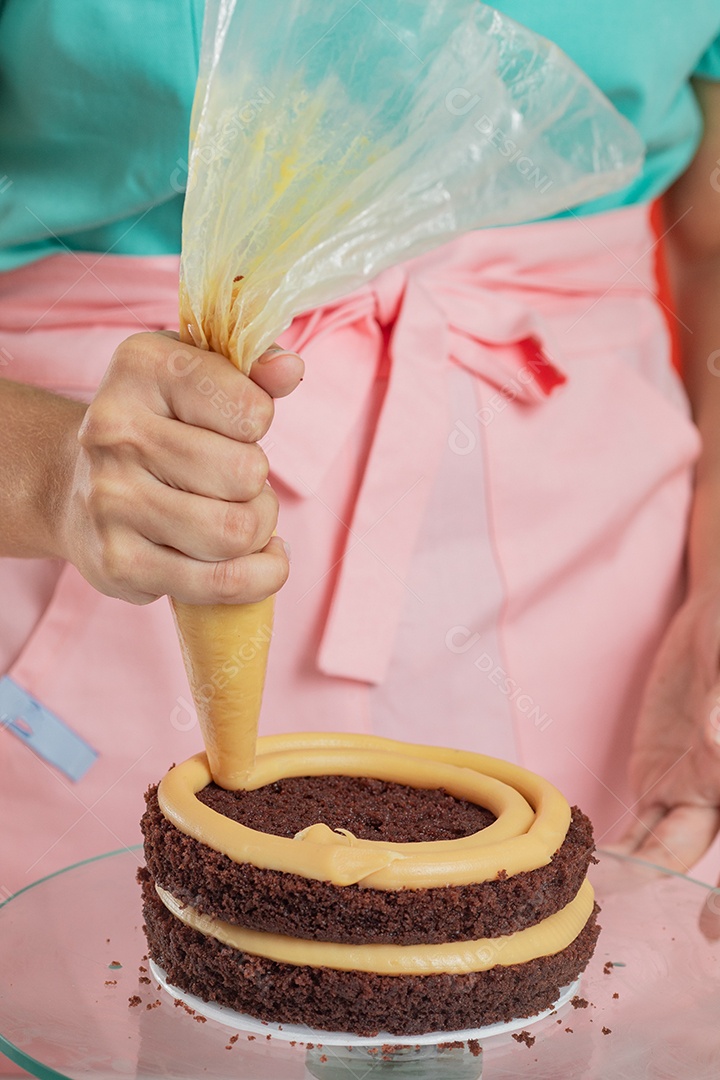 Linda mulher jovem chefe de cozinha preparando bolo
