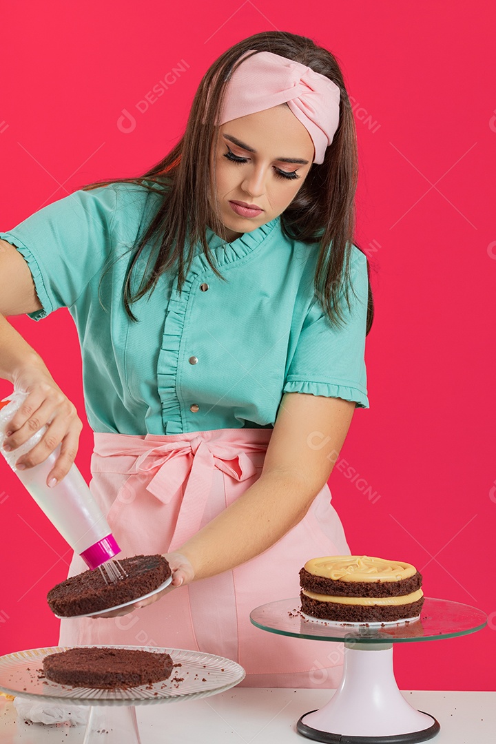 Linda mulher jovem chefe de cozinha preparando bolo