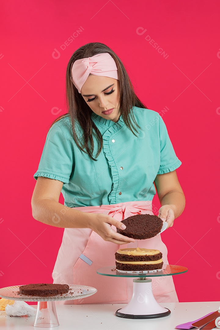 Linda mulher jovem chefe de cozinha preparando bolo