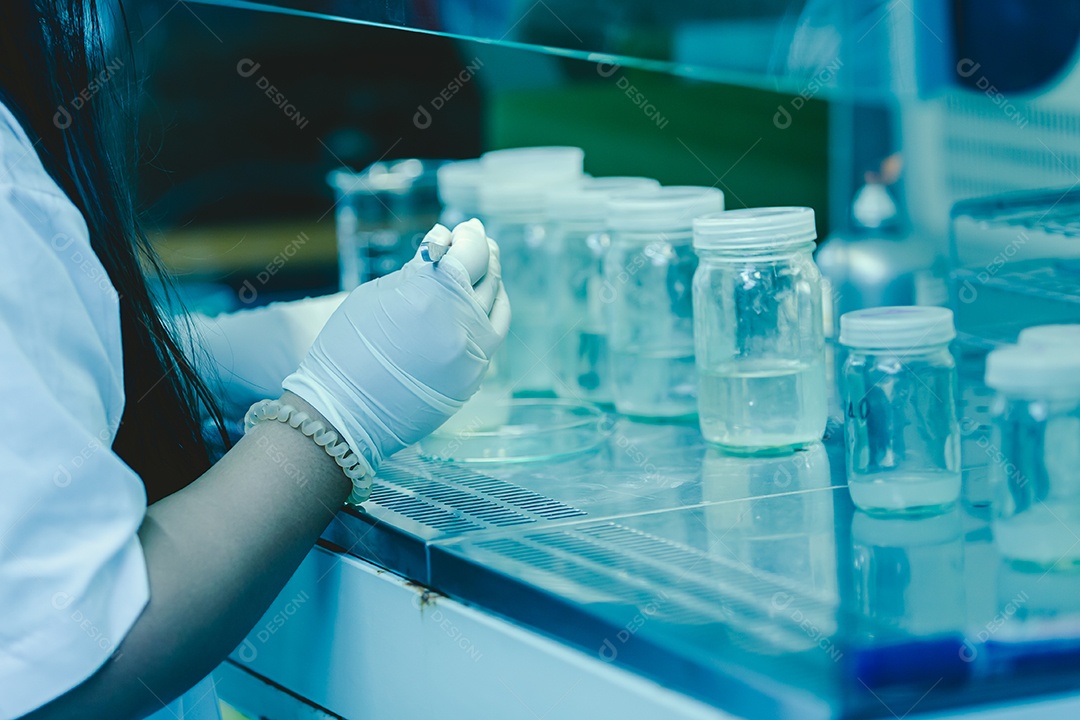 As mãos do cientista derramando solvente nas garrafas