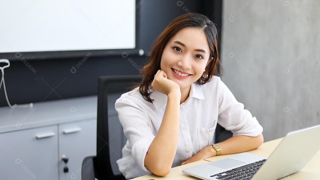 Empresária asiática sorrindo e usando seu laptop para trabalhar