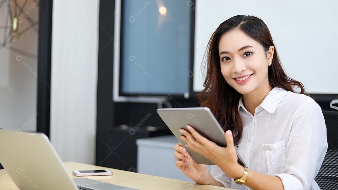 Empresária asiática sorridente usando tablet para trabalhar