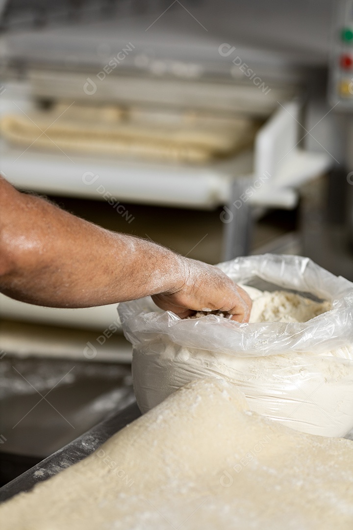 Mãos de homem pegando farinha branca sobre um saco plástico