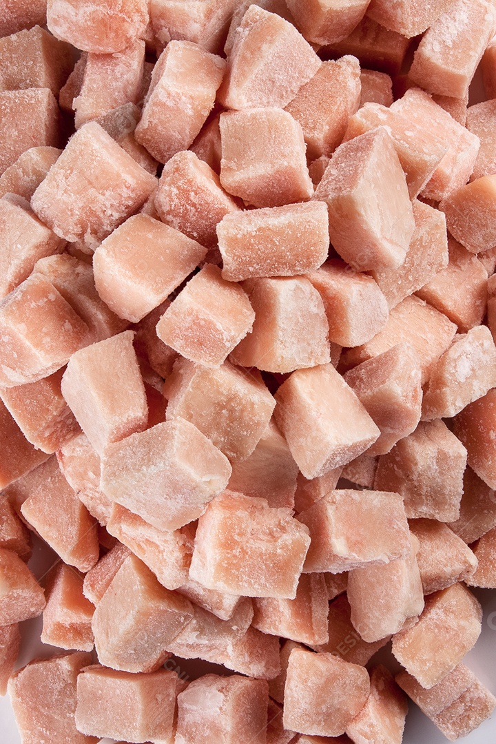 Cubos de carne de frango congelados isolados no fundo branco.