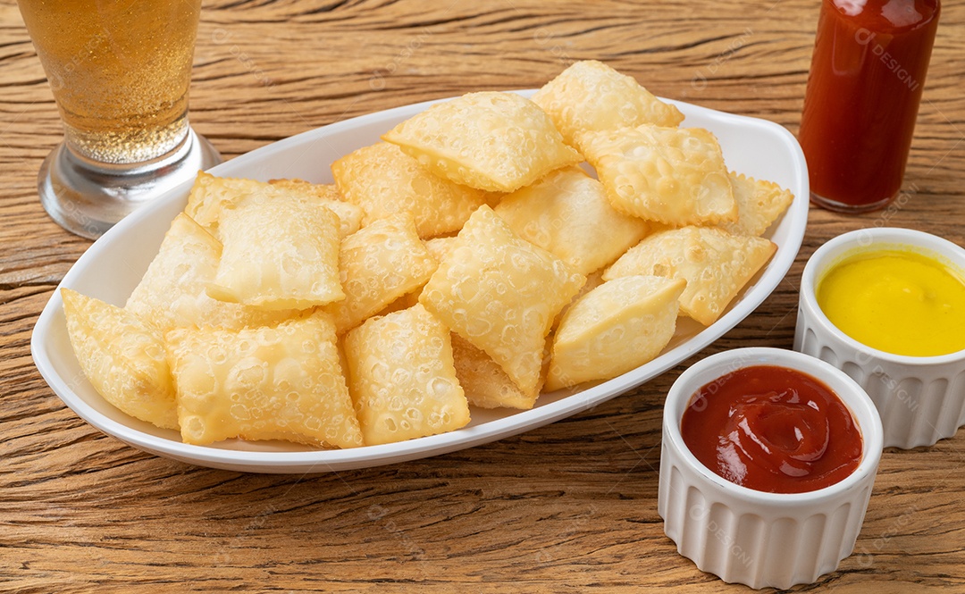 Pastel, petiscos típicos brasileiros sobre a mesa de madeira.