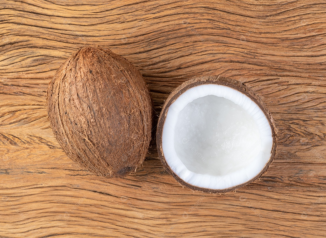 Coco e meia fruta rachada sobre a mesa de madeira.