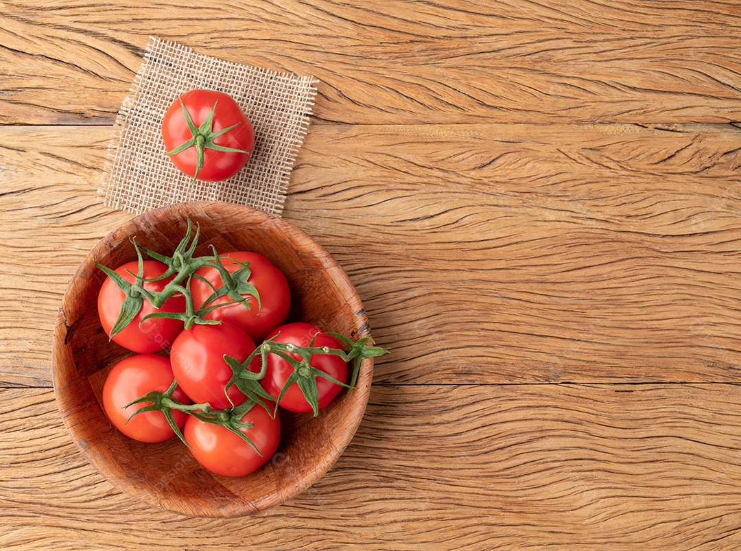 Tomates vermelhos em uma tigela sobre a mesa de madeira