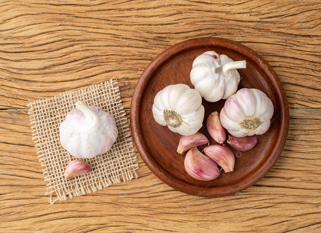 Bulbo de alho e cravo em um prato sobre a mesa de madeira.