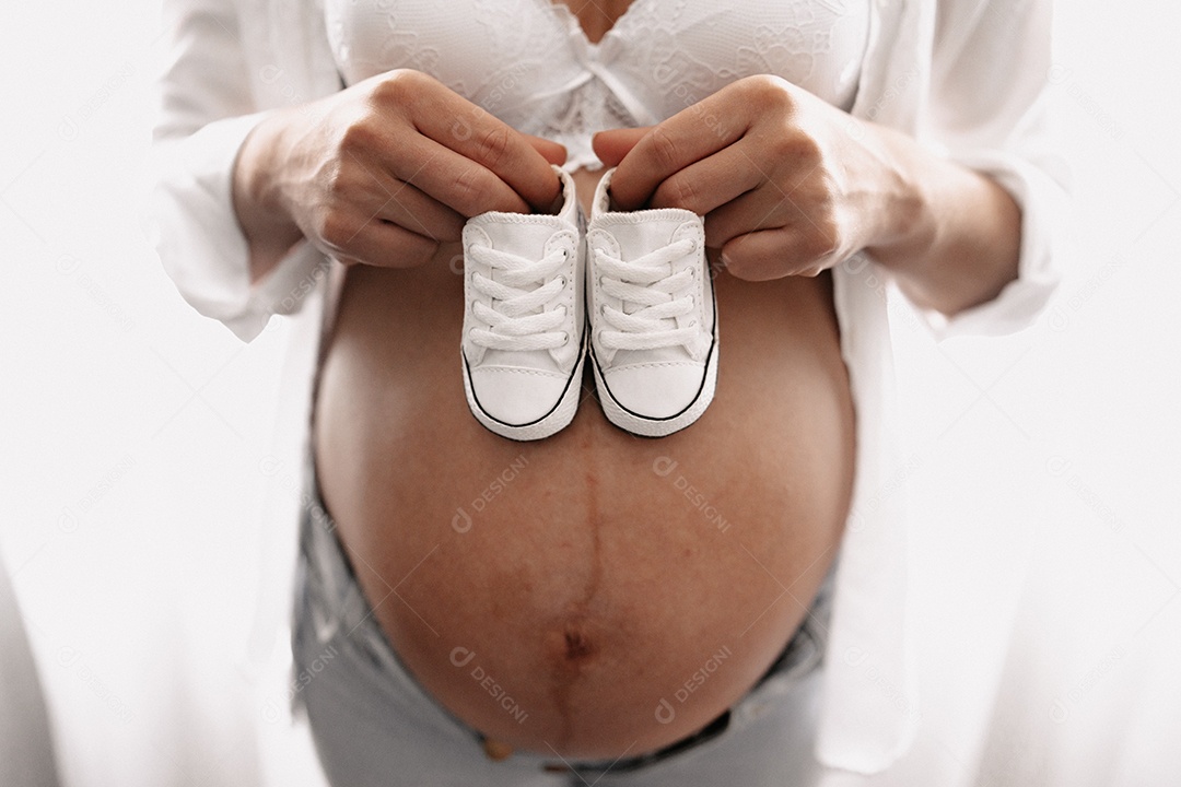 Mulher grávida acariciando sua barriga de 8 meses.