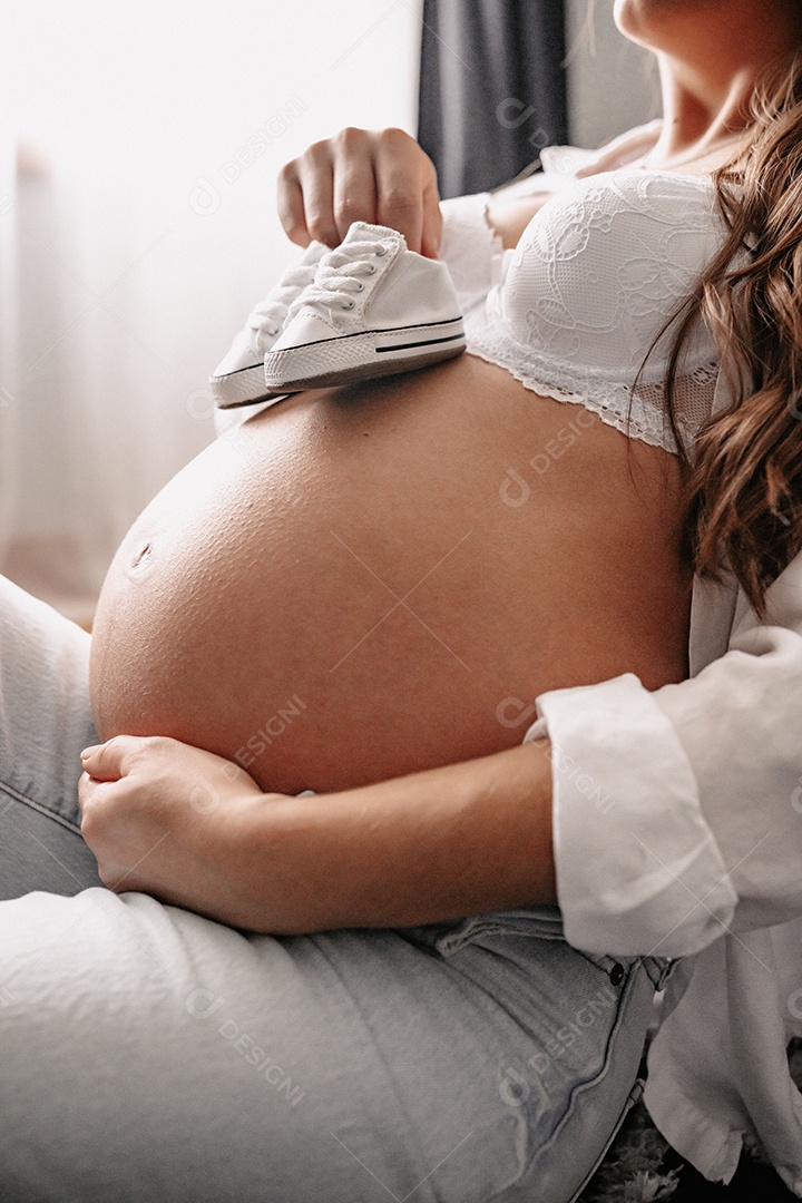 Mulher grávida acariciando sua barriga de 8 meses.