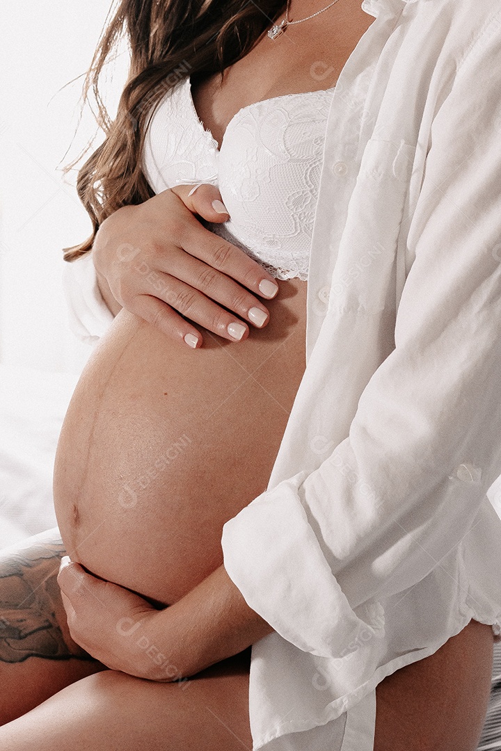 Mulher grávida acariciando sua barriga de 8 meses.