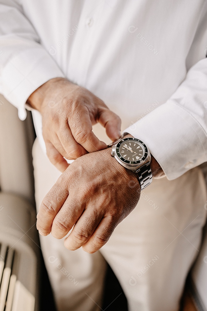 Empresário de camisa branca consertando seu relógio para ir trabalhar.