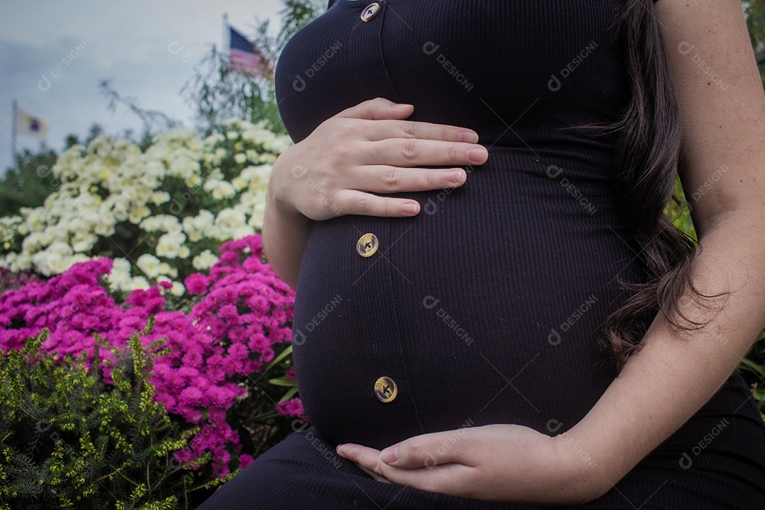 Mulher grávida com roupa preta e acariciando sua barriga com fluxo.