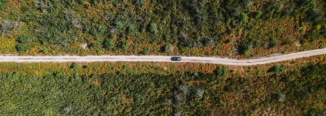 Tiro de drone de um carro dirigindo em uma estrada de terra em uma montanha