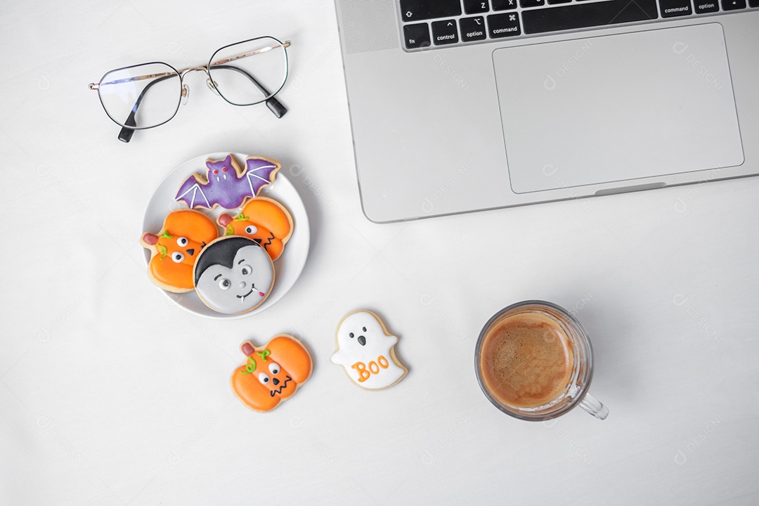 Biscoitos de Halloween, café quente e laptop de computador na parte traseira branca