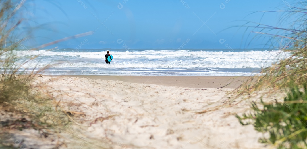 Paisagem de praia com surfista pronto para bater as ondas - As viagens de verão se encaixam no estilo de vida ativo.