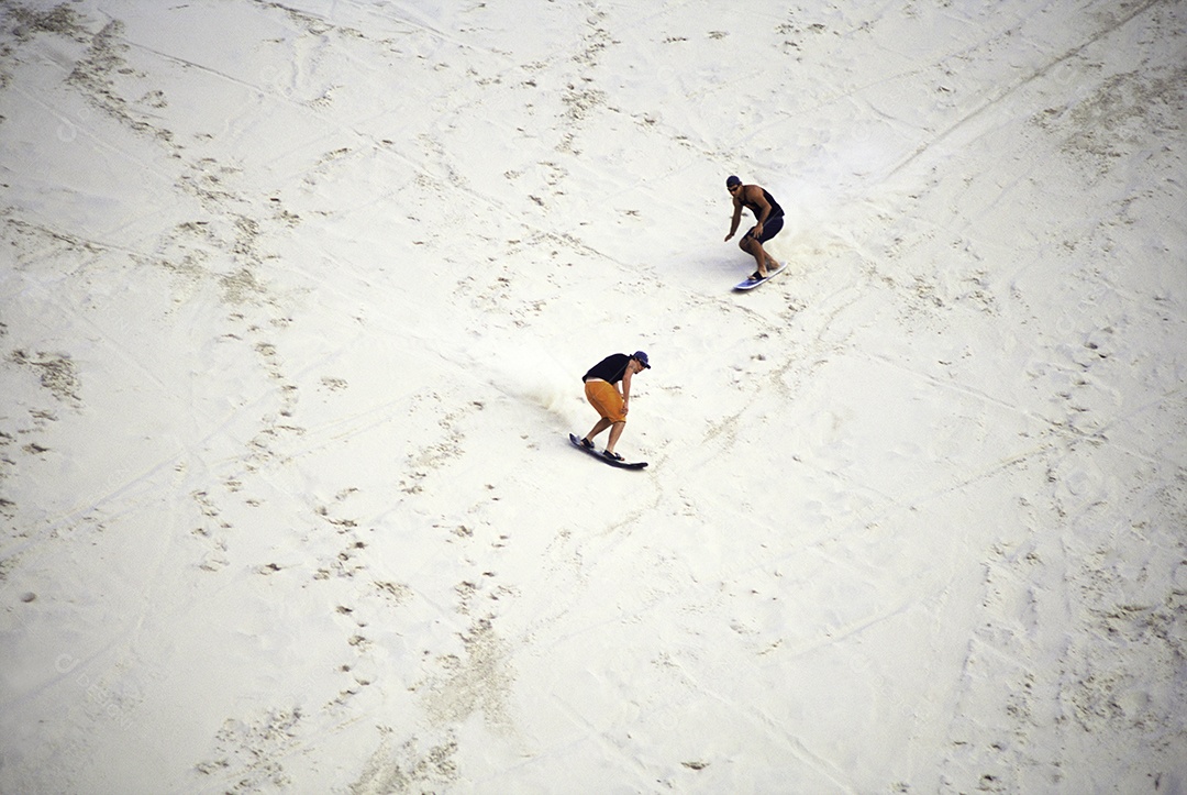 Vista de cima pessoas surfando sobre dunas de areia