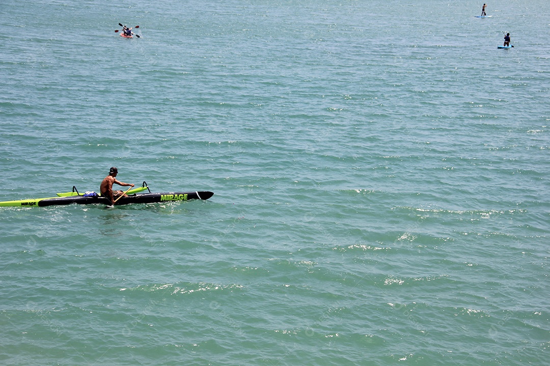 Homem sentado em caiaque no mar de aguas azuis