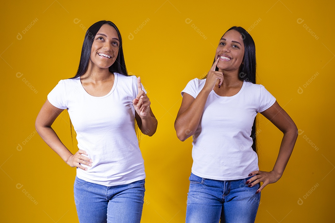 Lindas mulheres irmãs gêmeas jovens sobre fundo amarelo