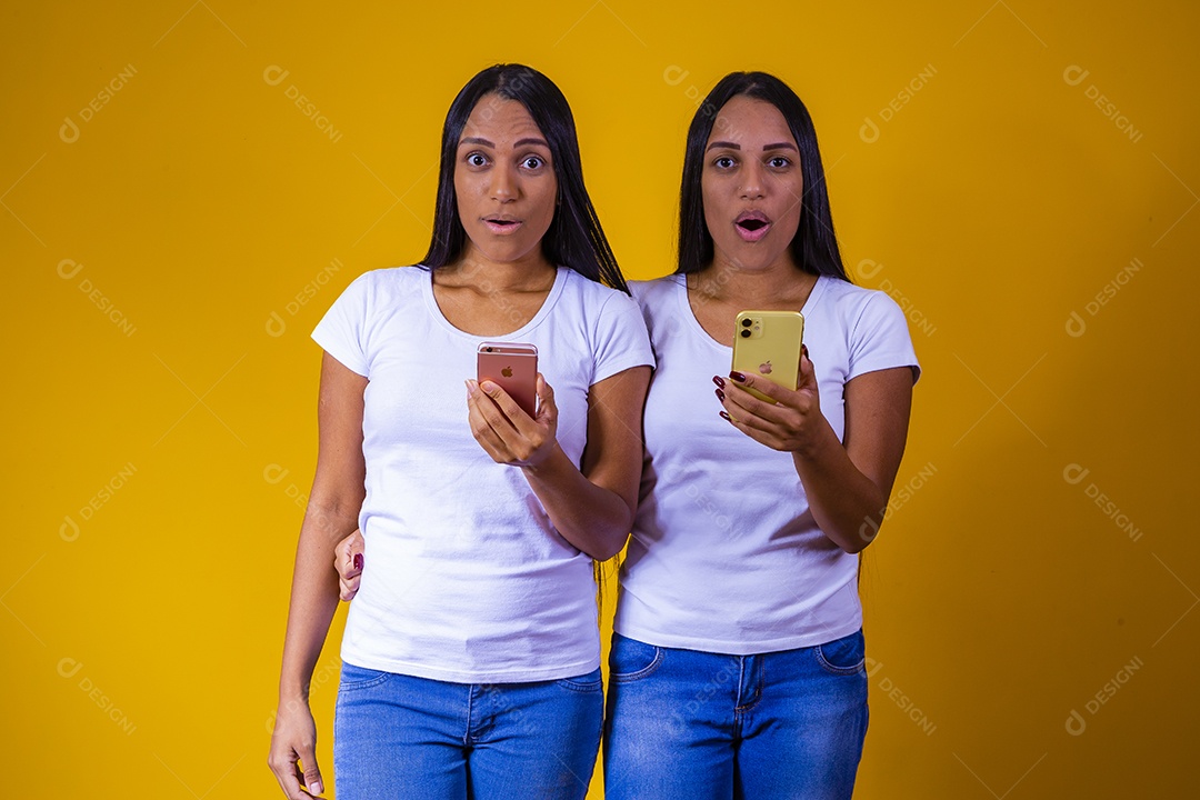 Lindas mulheres irmãs gêmeas jovens sobre fundo amarelo