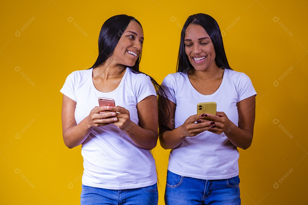 Lindas mulheres irmãs gêmeas jovens sobre fundo amarelo