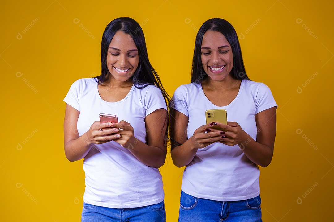 Lindas mulheres irmãs gêmeas jovens sobre fundo amarelo