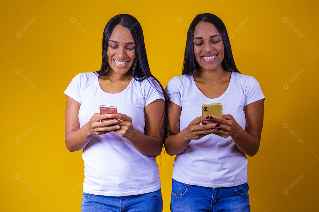 Lindas mulheres irmãs gêmeas jovens sobre fundo amarelo