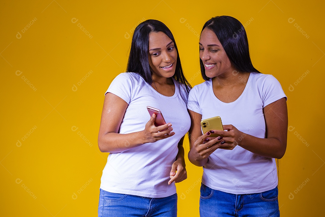 Lindas mulheres irmãs gêmeas jovens sobre fundo amarelo