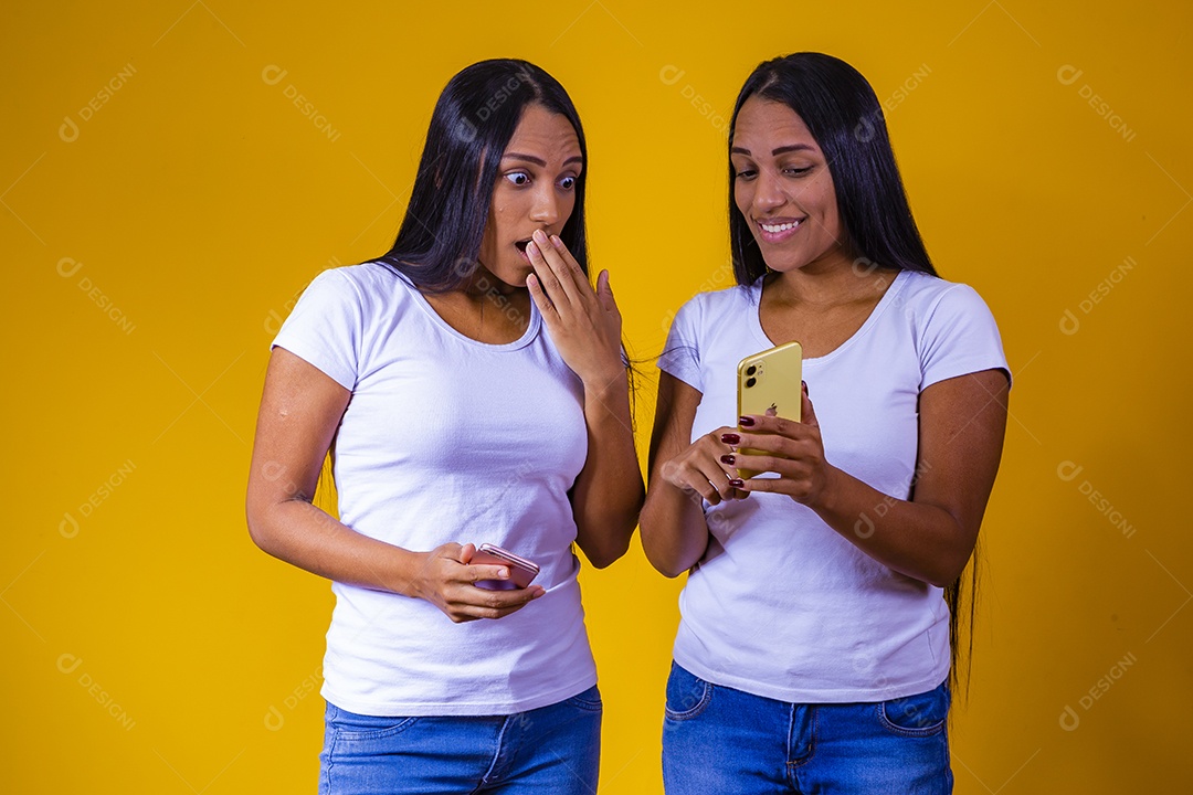 Lindas mulheres irmãs gêmeas segurando celular