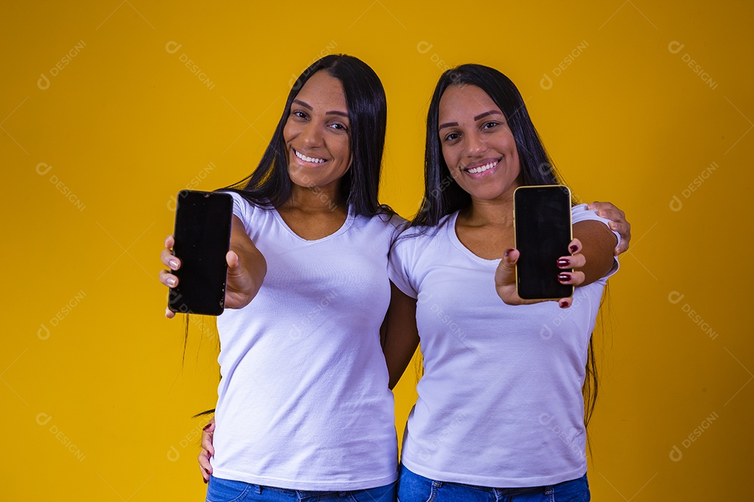 Lindas mulheres irmãs gêmeas segurando celular