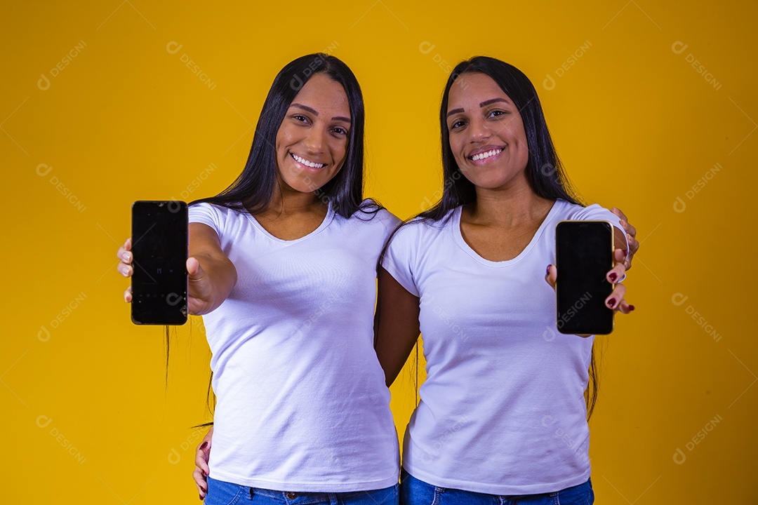 Lindas mulheres irmãs gêmeas segurando celular