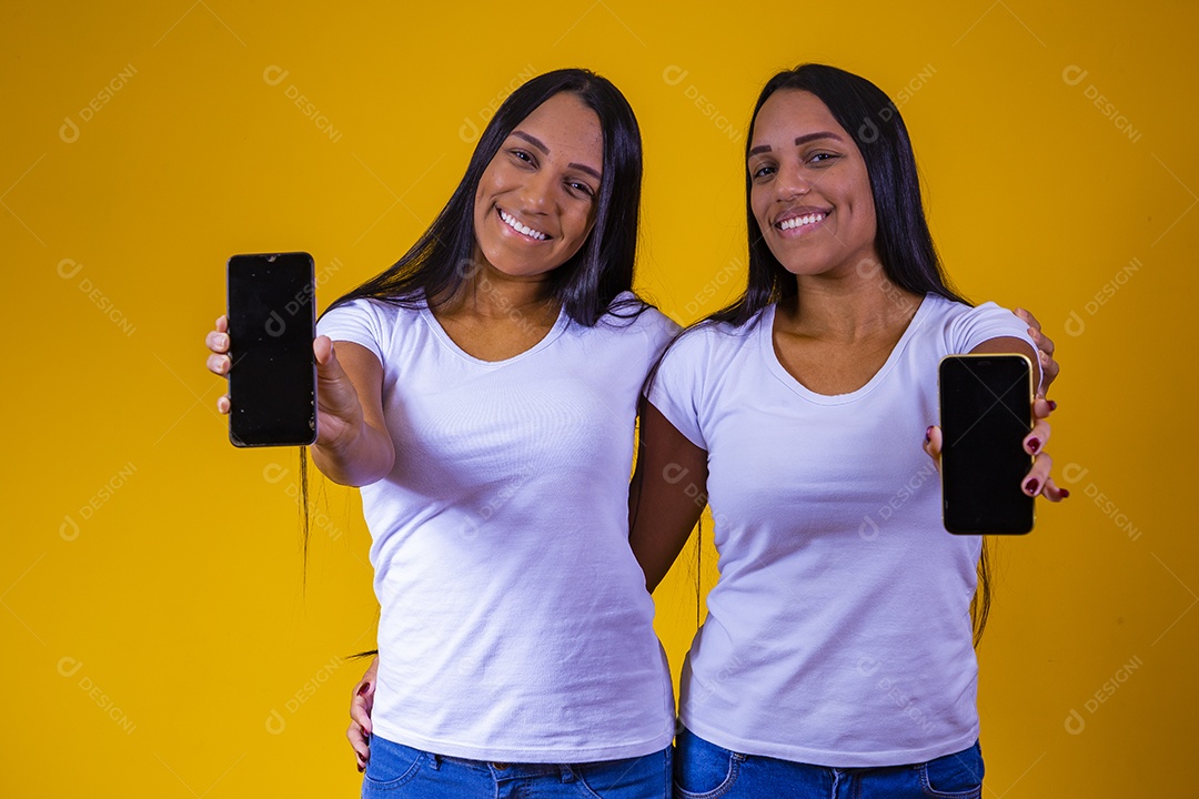 Lindas mulheres irmãs gêmeas segurando celular
