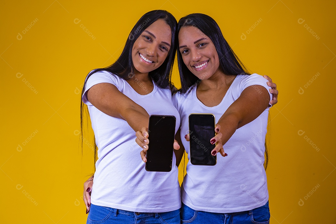 Lindas mulheres irmãs gêmeas segurando celular