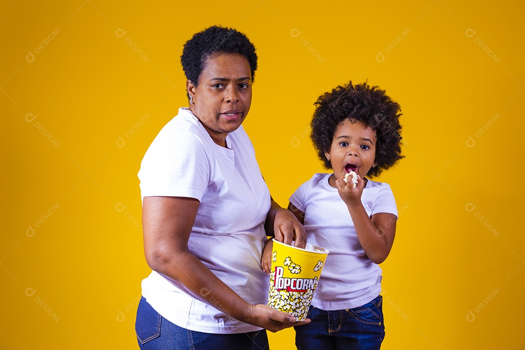 Mãe segurando balde pipoca assistindo filme com sua filha