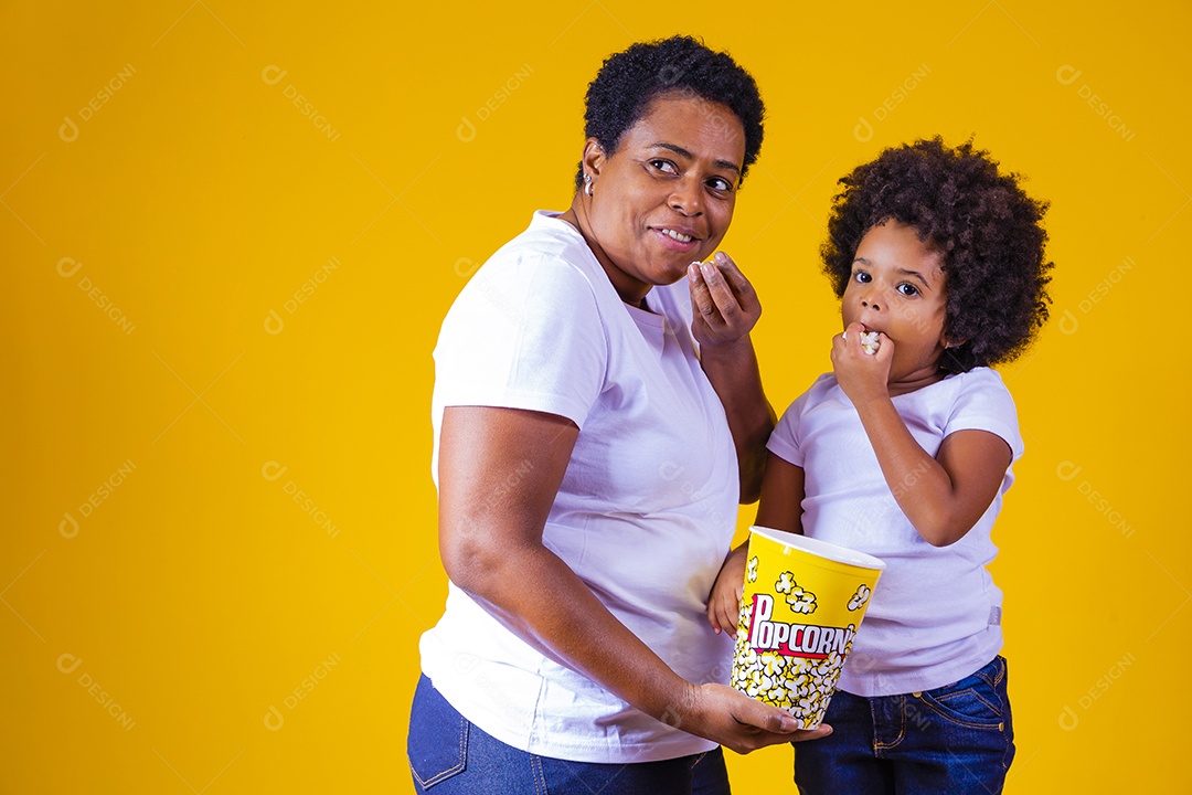 Mãe segurando balde pipoca assistindo filme com sua filha