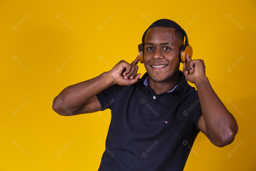 Homem jovem moreno sorridente e alegre ouvindo musica fone de ouvido