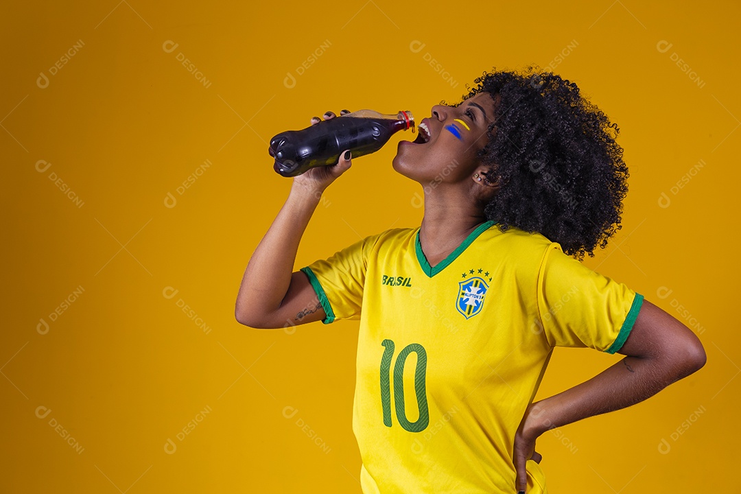 Linda mulher jovem torcedora usando camiseta brasil bebendo coca cola