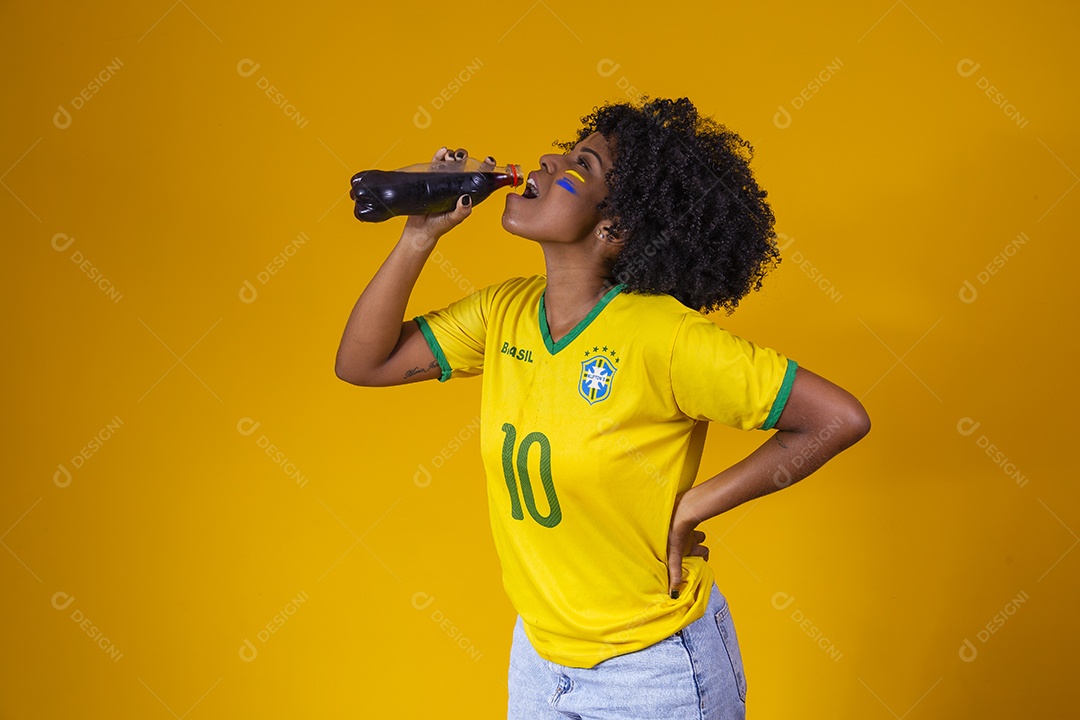 Linda mulher jovem torcedora usando camiseta brasil bebendo coca cola
