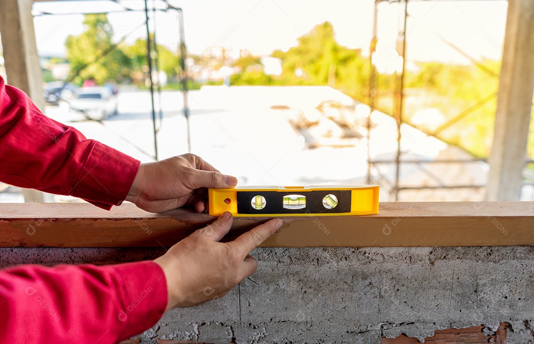Estucador em uniforme de trabalho vermelho verifique o saldo da janela de madeira.