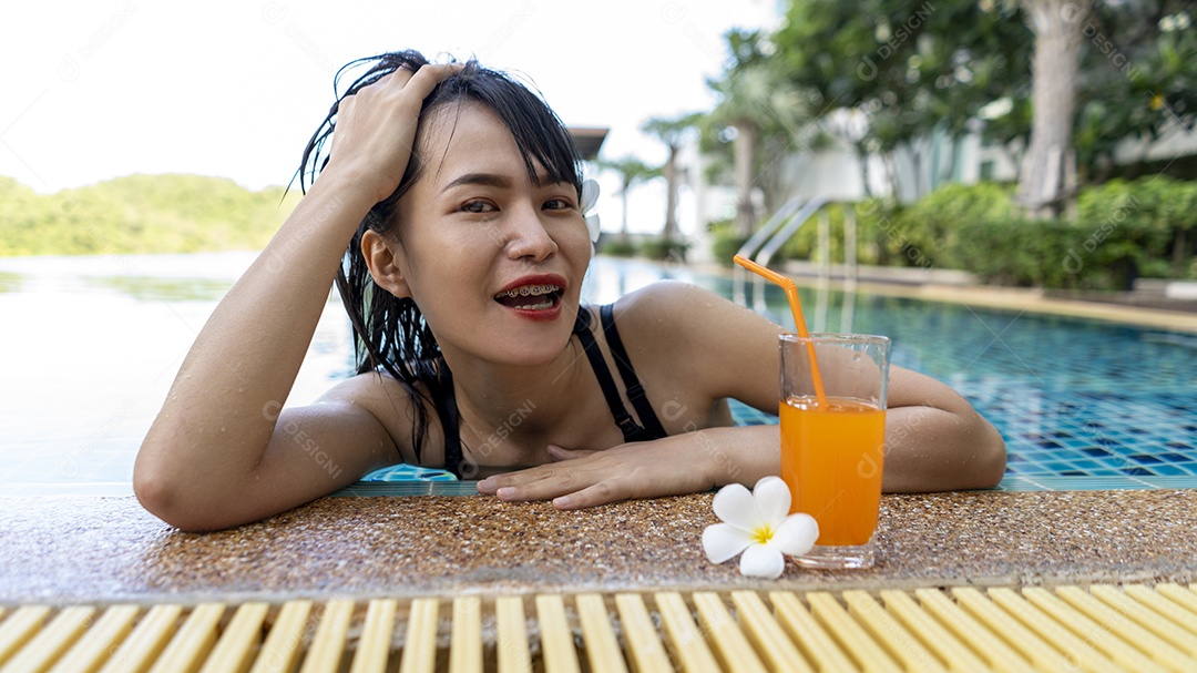 Relaxamento de mulher com suco de laranja na piscina no feriado de tempo livre.