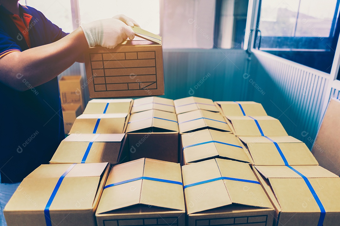 Mão de homem segurando a caixa de papelão colocando a caixa no palete de pilha.