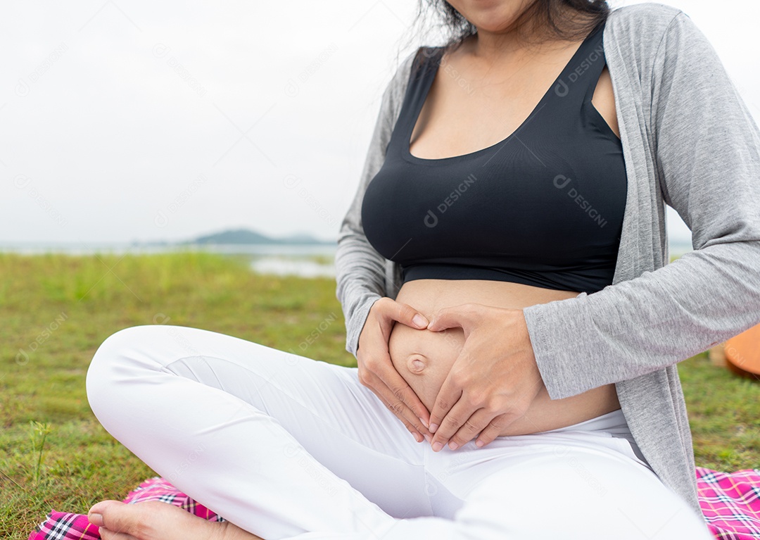 Mulher grávida tocando a barriga no jardim por amor e expectativa.