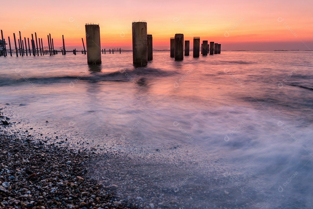 Casa à beira-mar e praia de pedra ao pôr do sol.