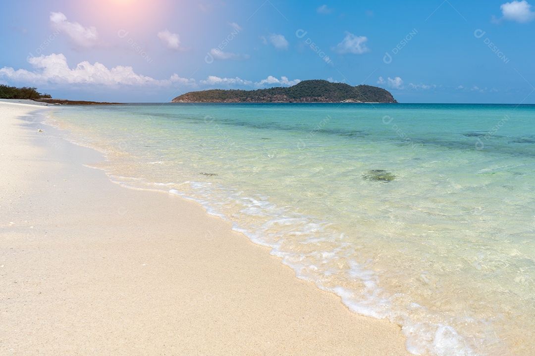 A praia de areia em dia ensolarado com a bela água do mar.