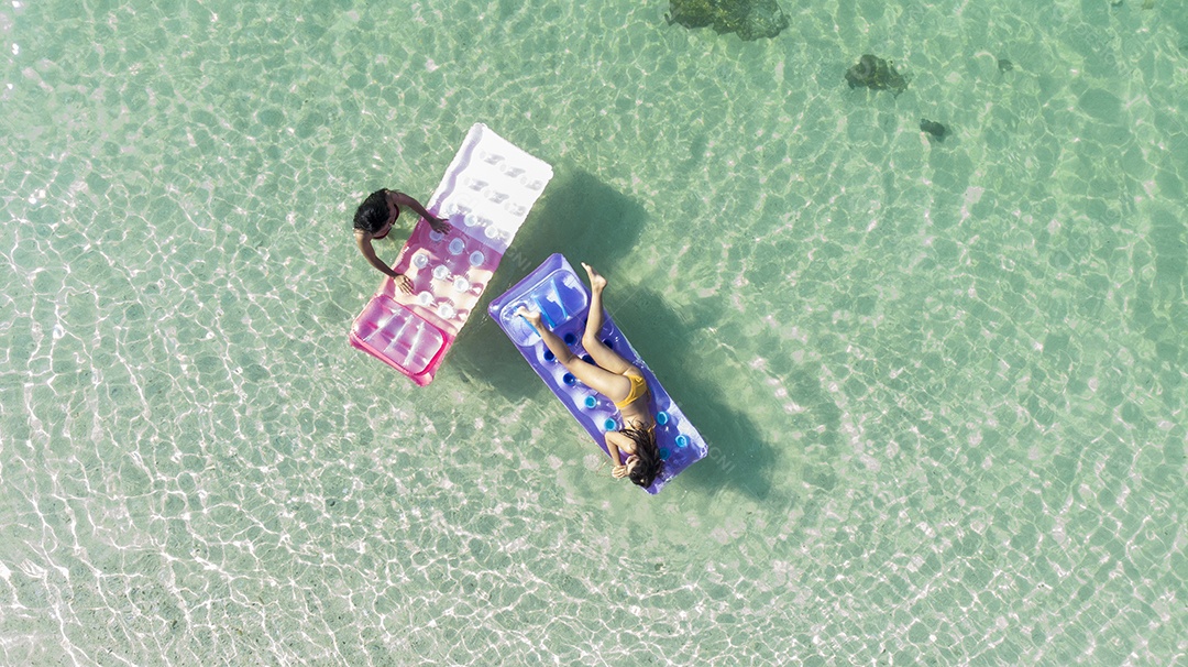 A mulher asiática relaxa tomando sol no sofá de ar.