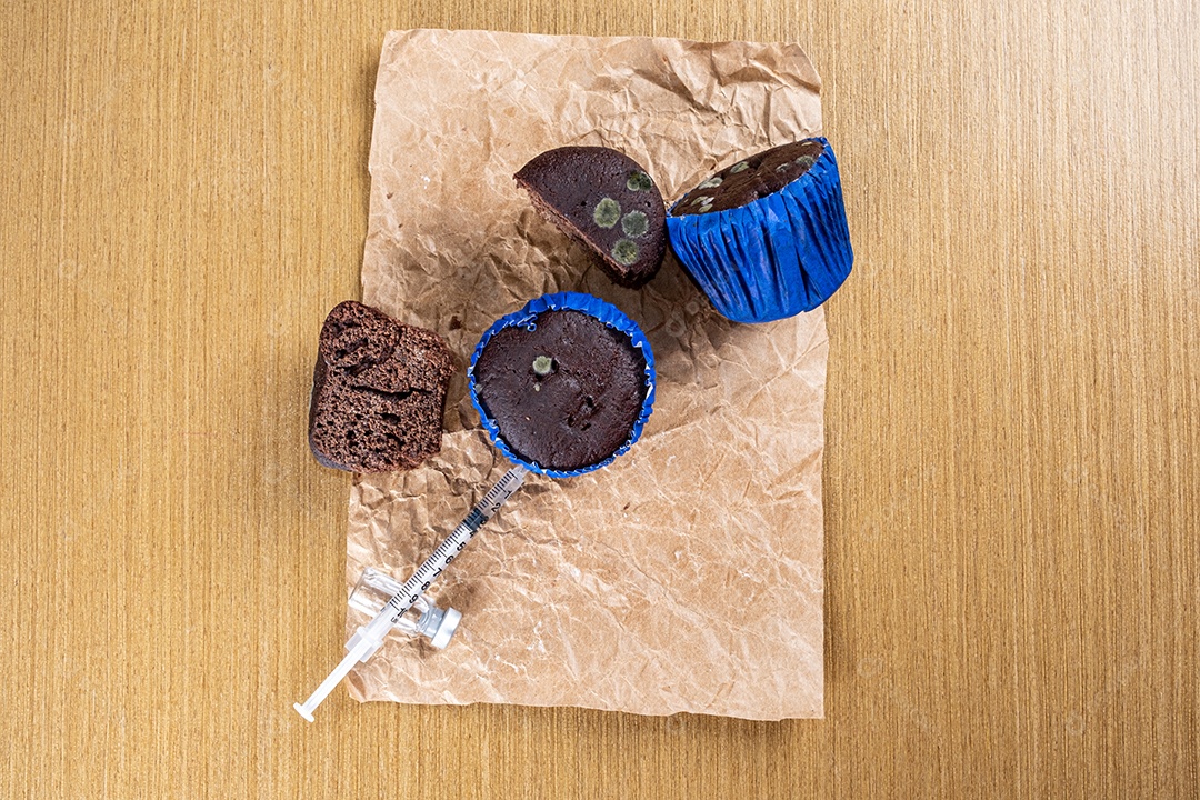 Seringa injetando insulina em bolo de chocolate mofado.