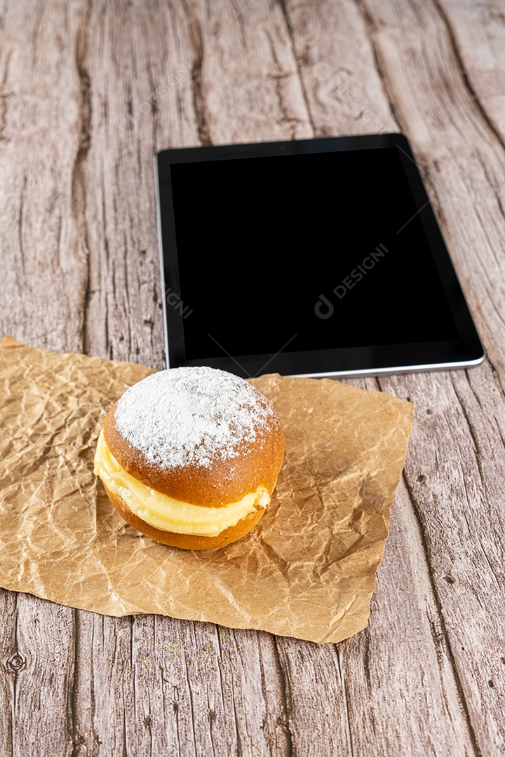 Rosquinhas de creme brasileiras em um papel pardo ao lado de um tablet.