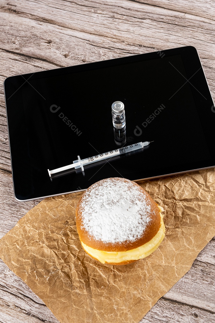Rosquinhas de creme brasileiras ao lado de uma seringa e ampola com insulina sobre a vista tablet