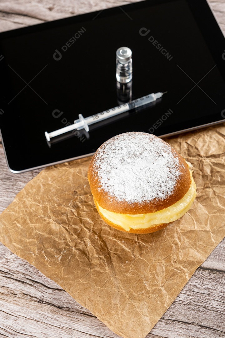 Rosquinhas de creme brasileiras ao lado de uma seringa e ampola com insulina sobre a vista tablet