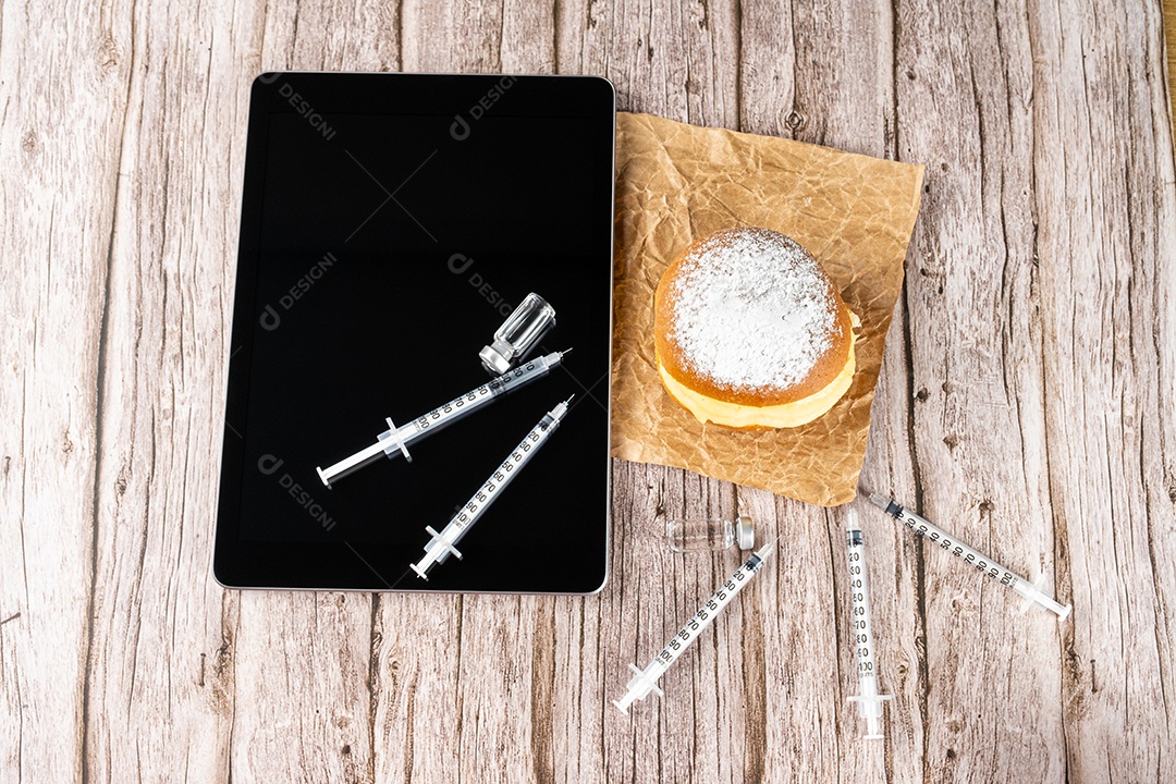 Rosquinhas de creme brasileiras cercadas por várias seringas e ampolas com insulina.